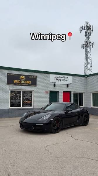 Black Porsche 718 Cayman with dark automotive window tint parked outside WPEG Customs window tint shop in Winnipeg